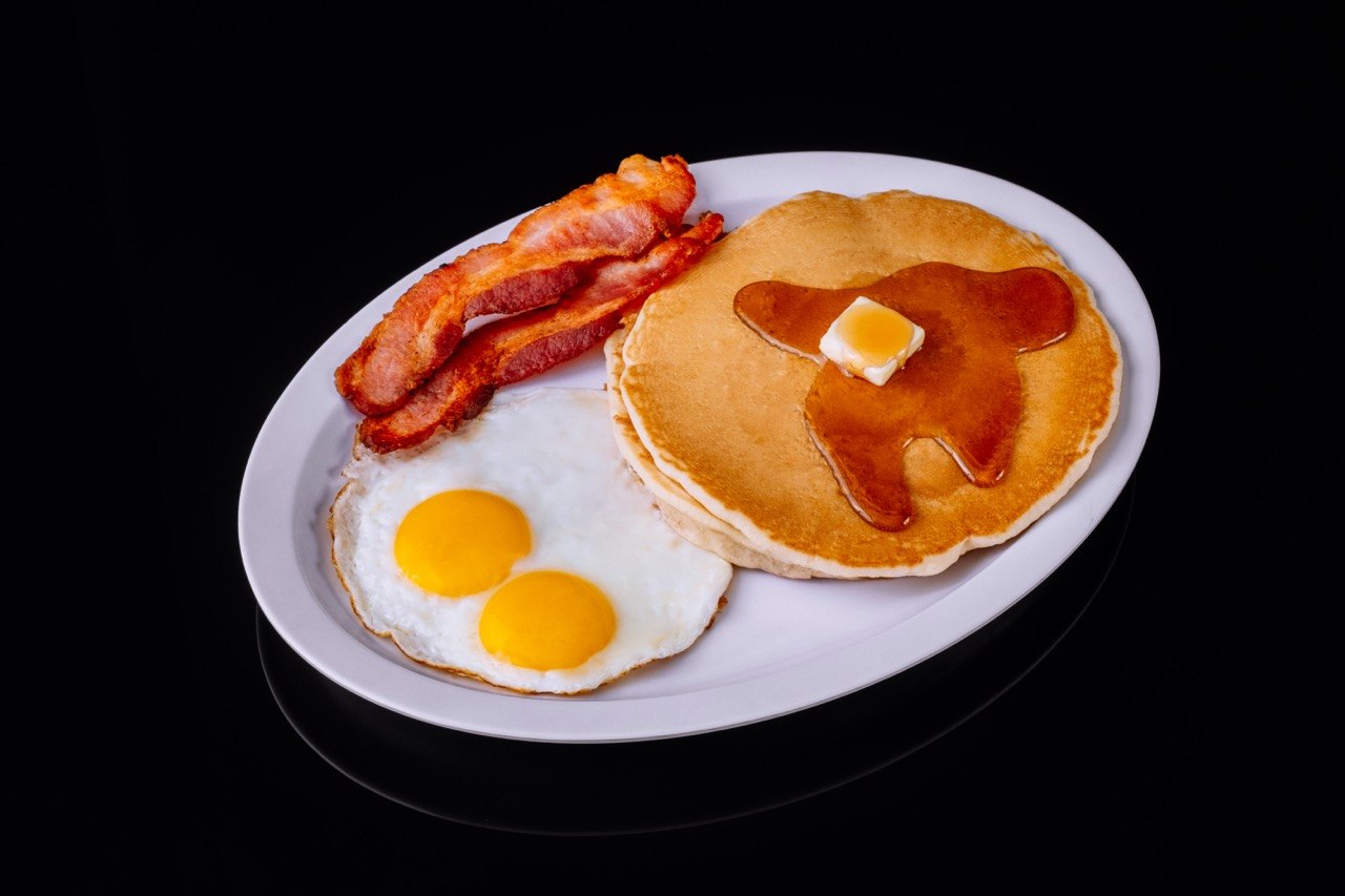 Tom's Jr. breakfast plate with two eggs, bacon, and pancakes