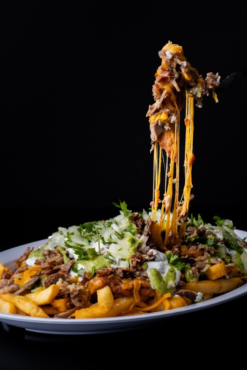 Tom's Jr. carne asada loaded fries with melted cheese, guacamole, and sour cream